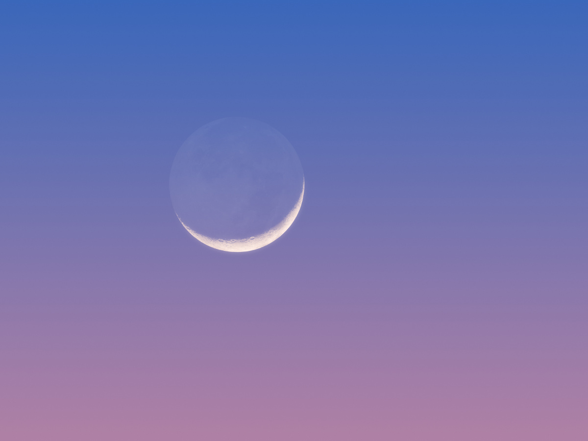 傍晚蓝紫色天空中的峨眉月