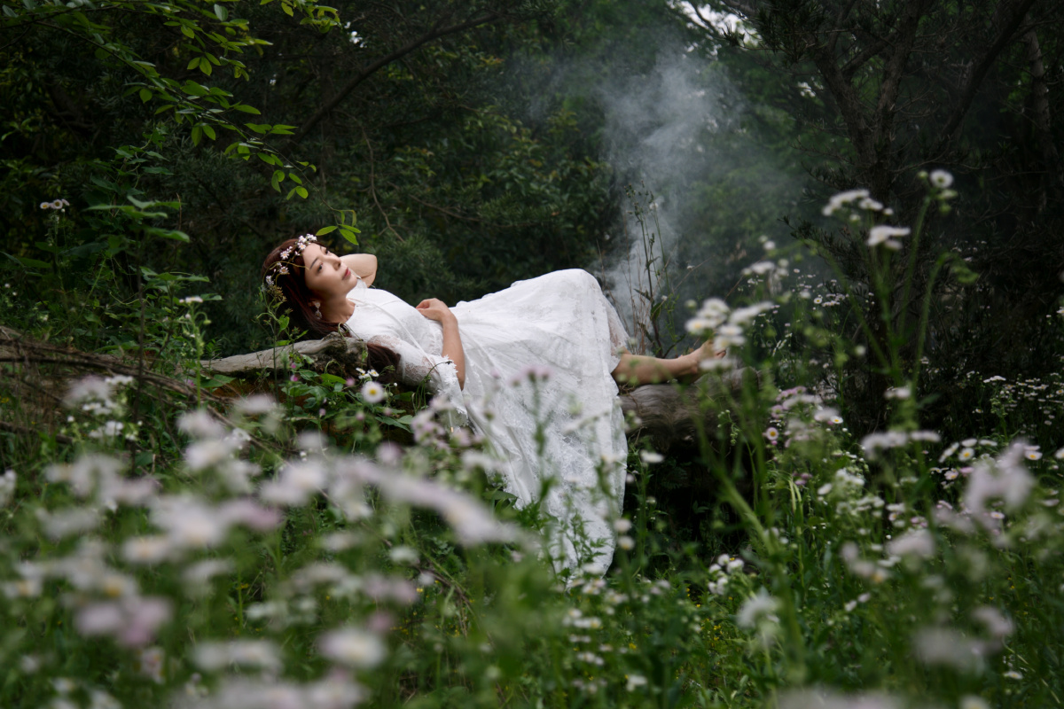 白衣女子半躺在森林中