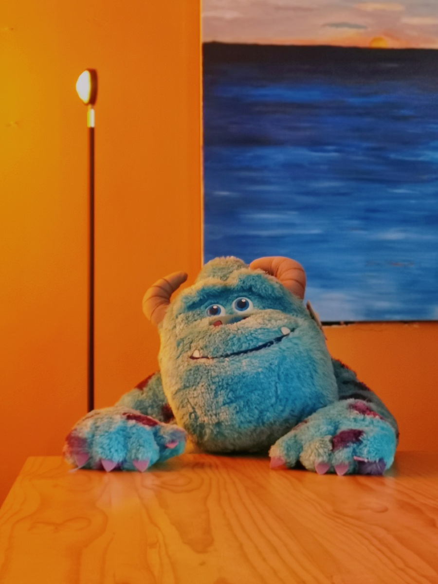 室内暖光下怪兽大学的蓝毛怪萨利文静静地坐在桌前