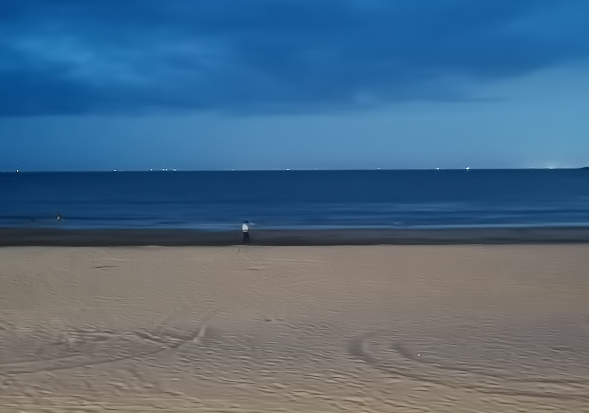 夜晚的海和沙滩,孤独的人站在中央.