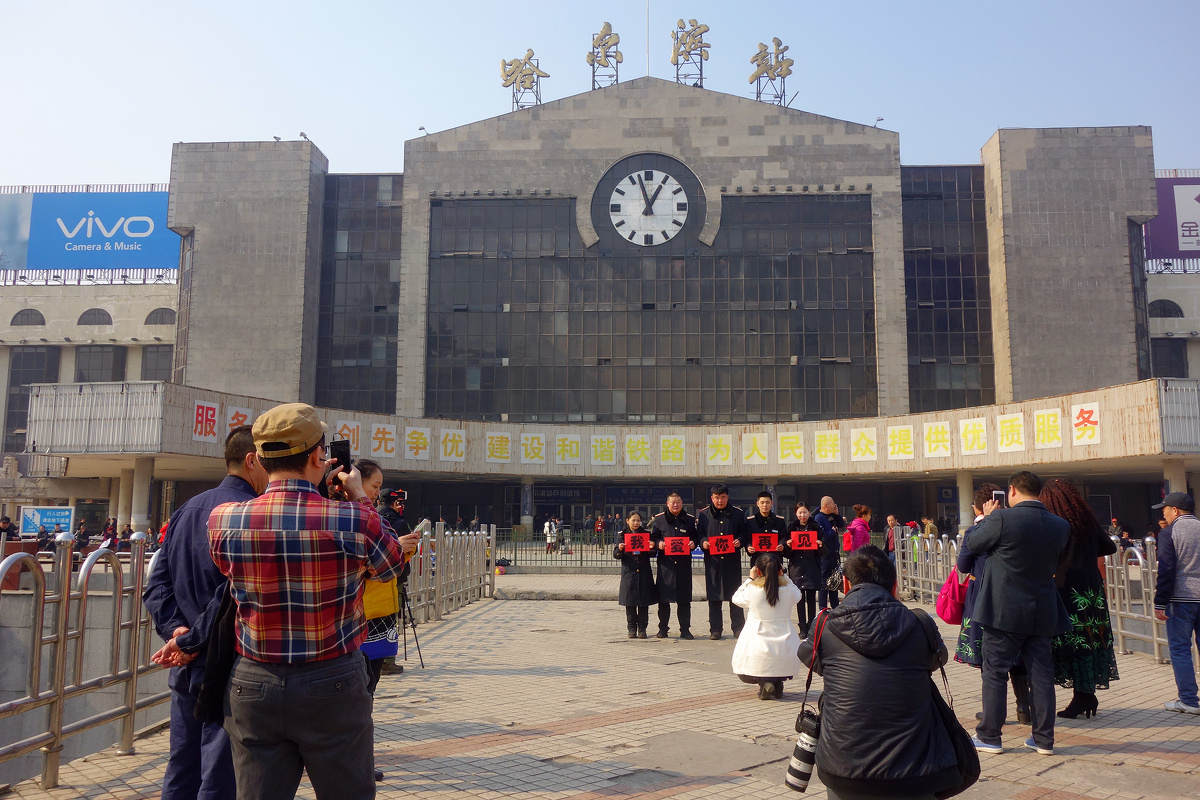 来哈尔滨站前留影的人们