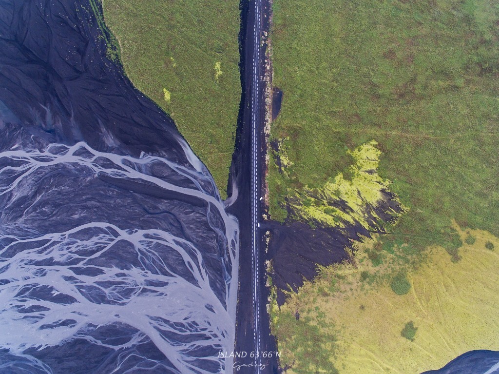 冰岛自驾，无人机从公路上方500米处俯瞰大地，左侧的滩涂与右侧的苔原地貌被公路隔开。从高空俯瞰，整条公路如拉链一般