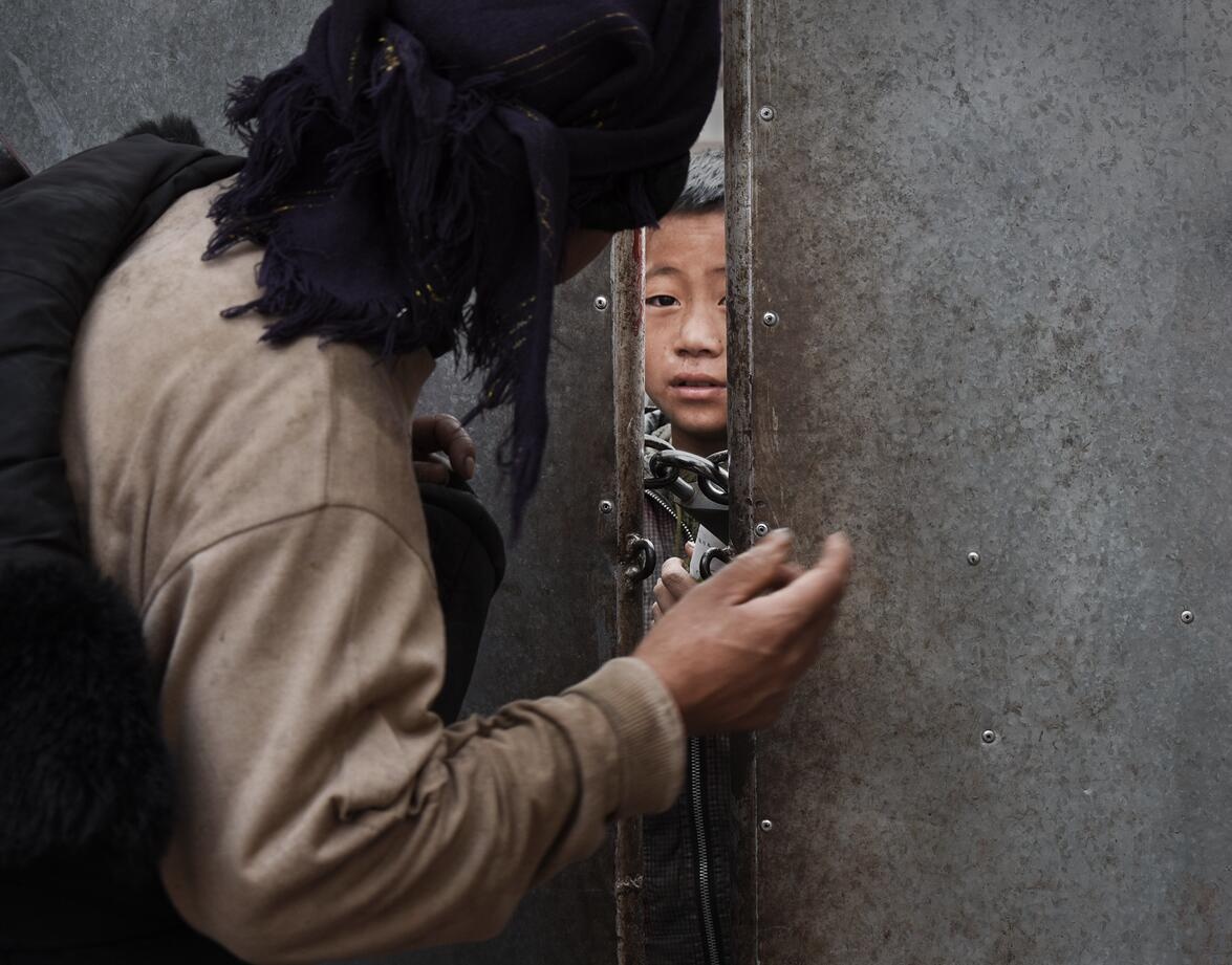 一位母亲去学校看小孩,在学校门缝里交代事情