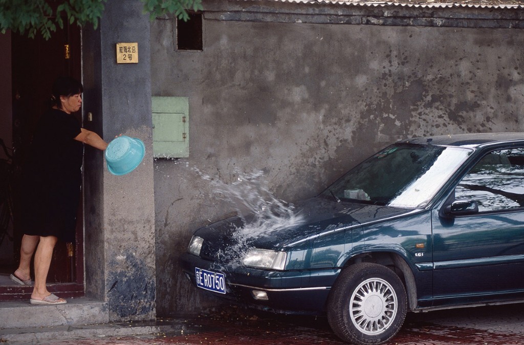 1999年摄于北京前海。当年此处，幽深静谧，百姓用车，富康、捷达是主流，停在四合院门口。洗车，当然用盆。器材：尼康F5，胶片：富士provia