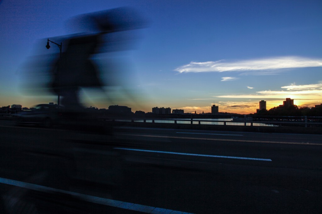 照片拍摄与波士顿查尔斯河上某桥，夕阳西下，来往于桥上人影车影，捕捉下这这瞬间