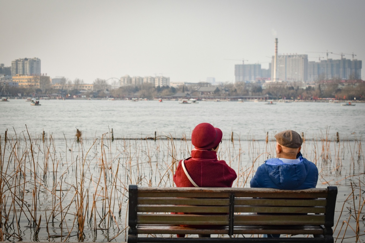 大明湖畔游玩,一对儿老人坐在湖边晒太阳