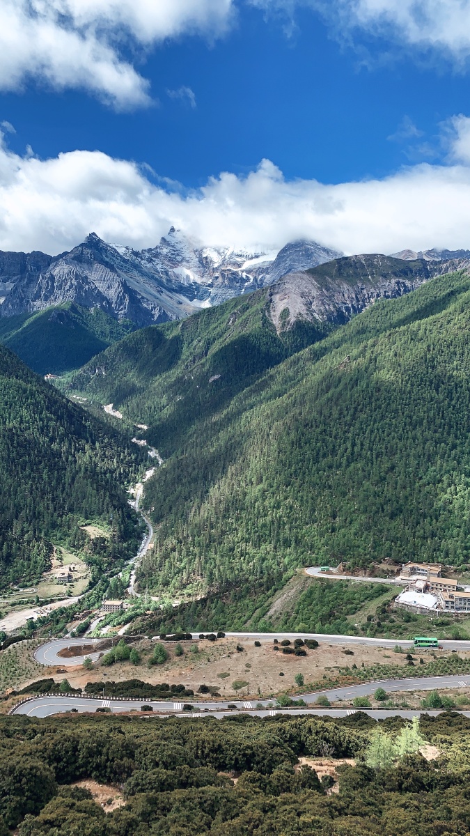 稻城亚丁远处巍峨的雪山加上蜿蜒的山路仿佛通向众神之地