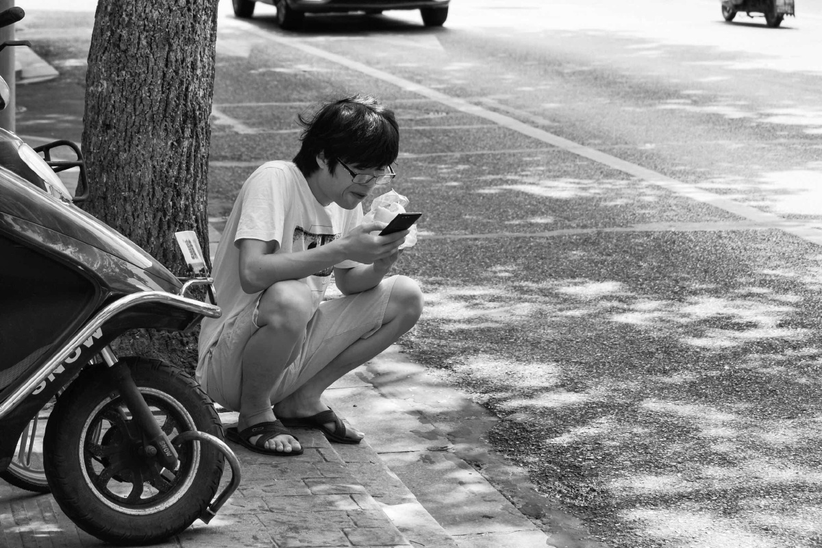 蹲在路边吃馒头的年轻人