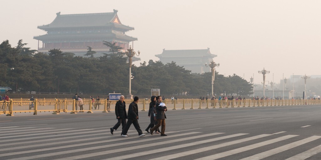 前三门大街前,正从天安门广场上离开的游客。远处的正阳门被雾霾里的夕阳染上昏黄的金色。