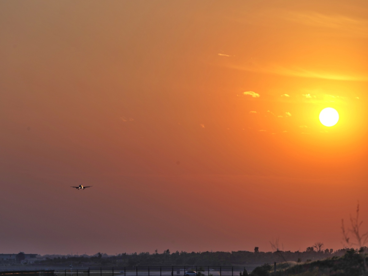 夏日傍晚,夕阳西下,晚霞红满了天空,飞机缓缓落下.