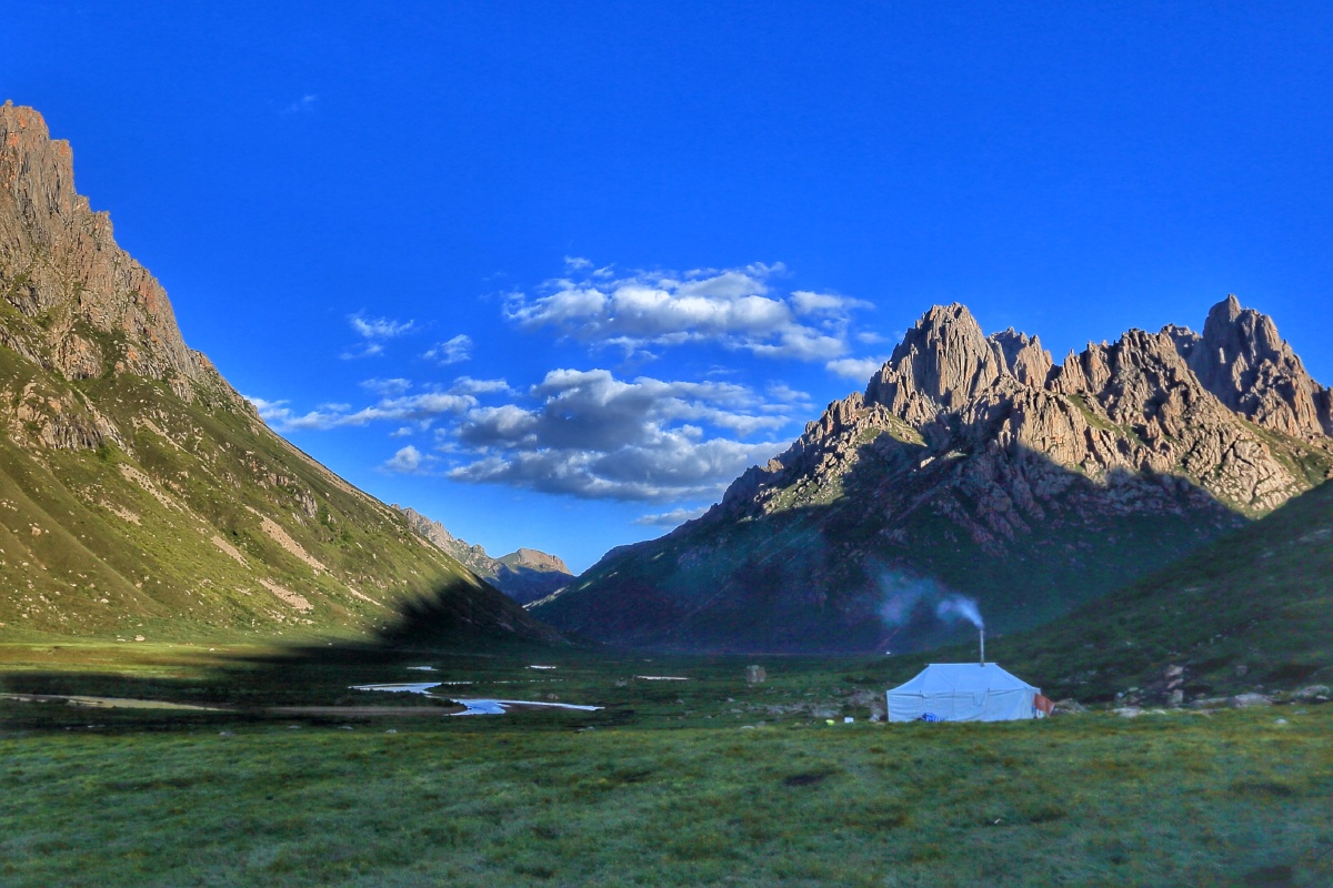 年保玉则,夕阳照耀着远山,蓝蓝的天白白的云,毡房里冒出一缕青烟,这是
