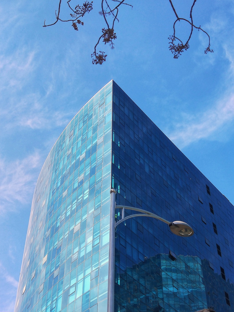 蓝天白云下的玻璃外墙大楼与蓝天白云相乎映