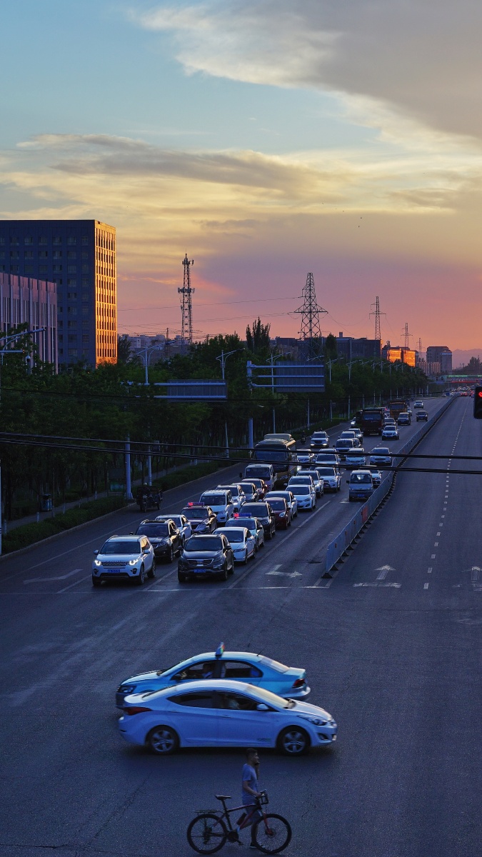 傍晚的街道车流攒动天空中的晚霞格外惹眼天桥上的人群中不时有人驻足