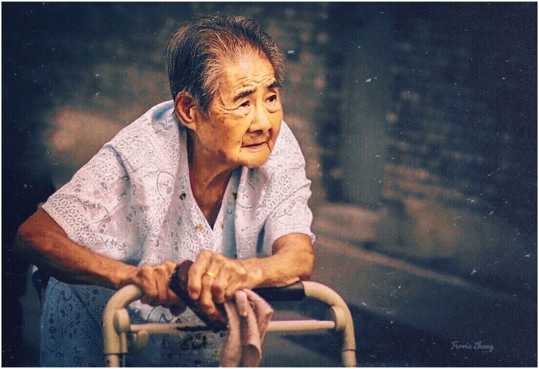 胡同口,一位老人推着婴儿车改装的"拐杖",迎着夕阳走去.