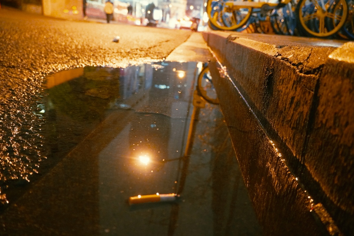 在阴暗的角落,烟蒂静静的躺在倒映路灯的水里