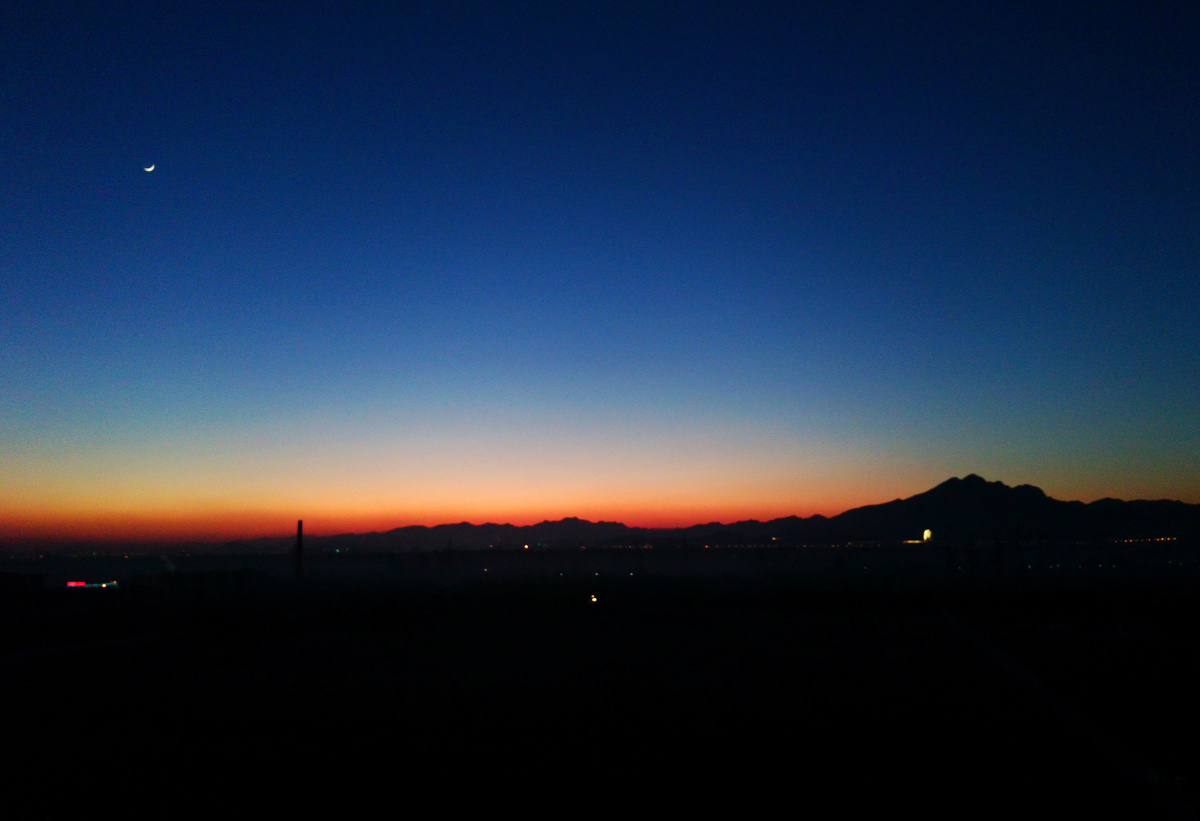太阳刚刚落山不久,天空呈蓝黑色,山间还有一层橘黄色的轻纱披在山上.