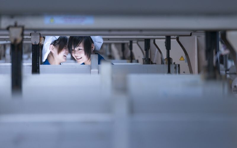 纺织车间的两个少女正在说着开心的悄悄话——