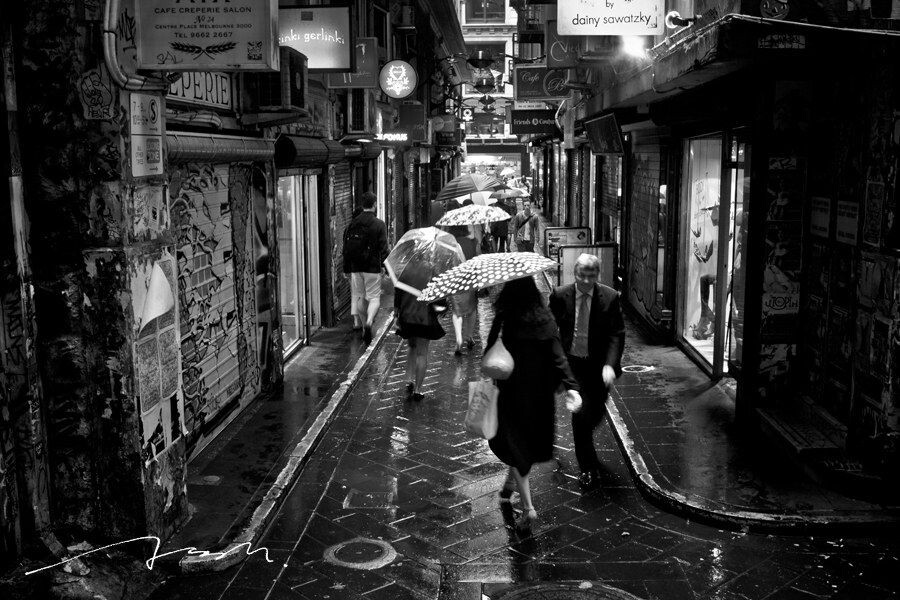 雨天，撑着伞的人走在Center Place的小巷中<br />
