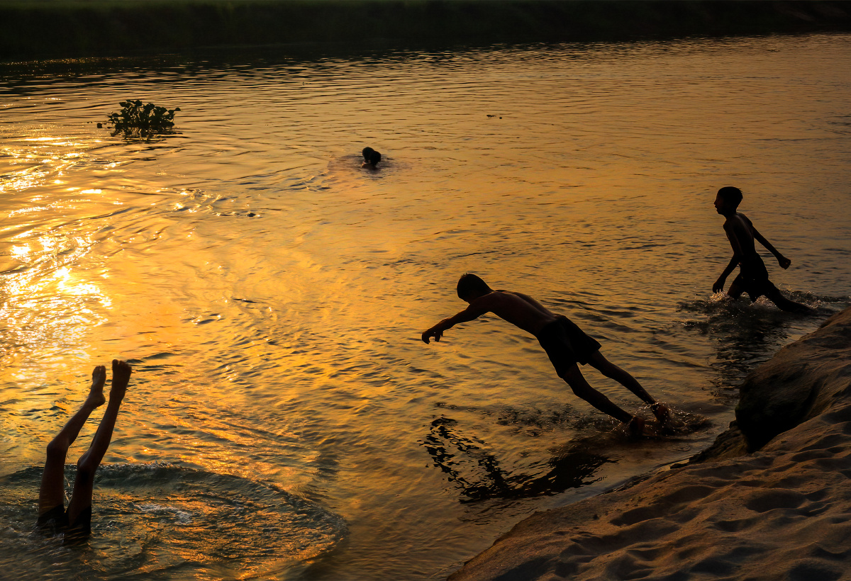 光影中行走在鳄鱼出没的河中嬉水的尼泊尔孩子组照之三