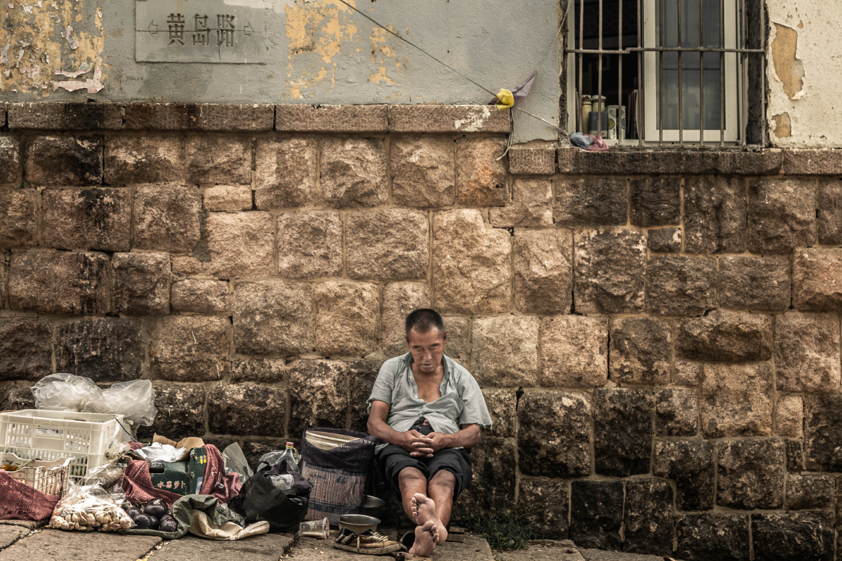 摄于青岛里院街头正午一个路边摆摊的大爷在休息