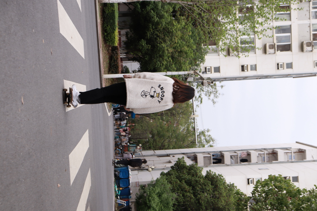 校园里滑滑板的少女和匆匆的人群