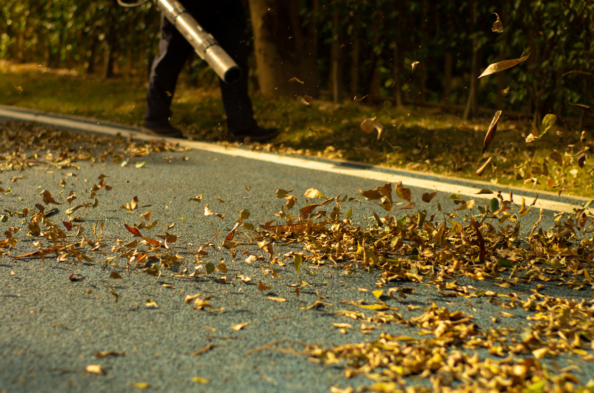 环卫作业-背着吹风机吹风扫落叶的环卫工人