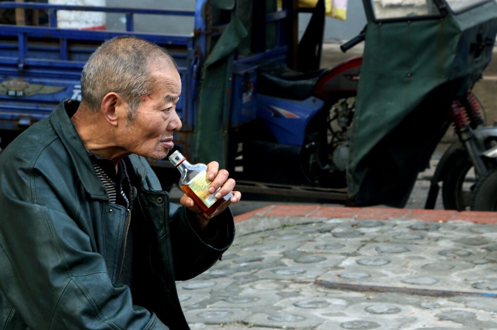 一位老人坐在路边喝着酒,眼神满是愁容,但为生计忙碌何尝不是一种快乐呢?【摄于长沙市街头】