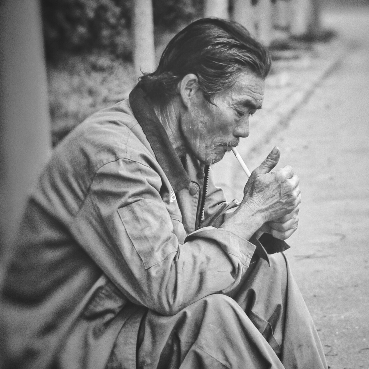 坐在路边等公交的老年农民工