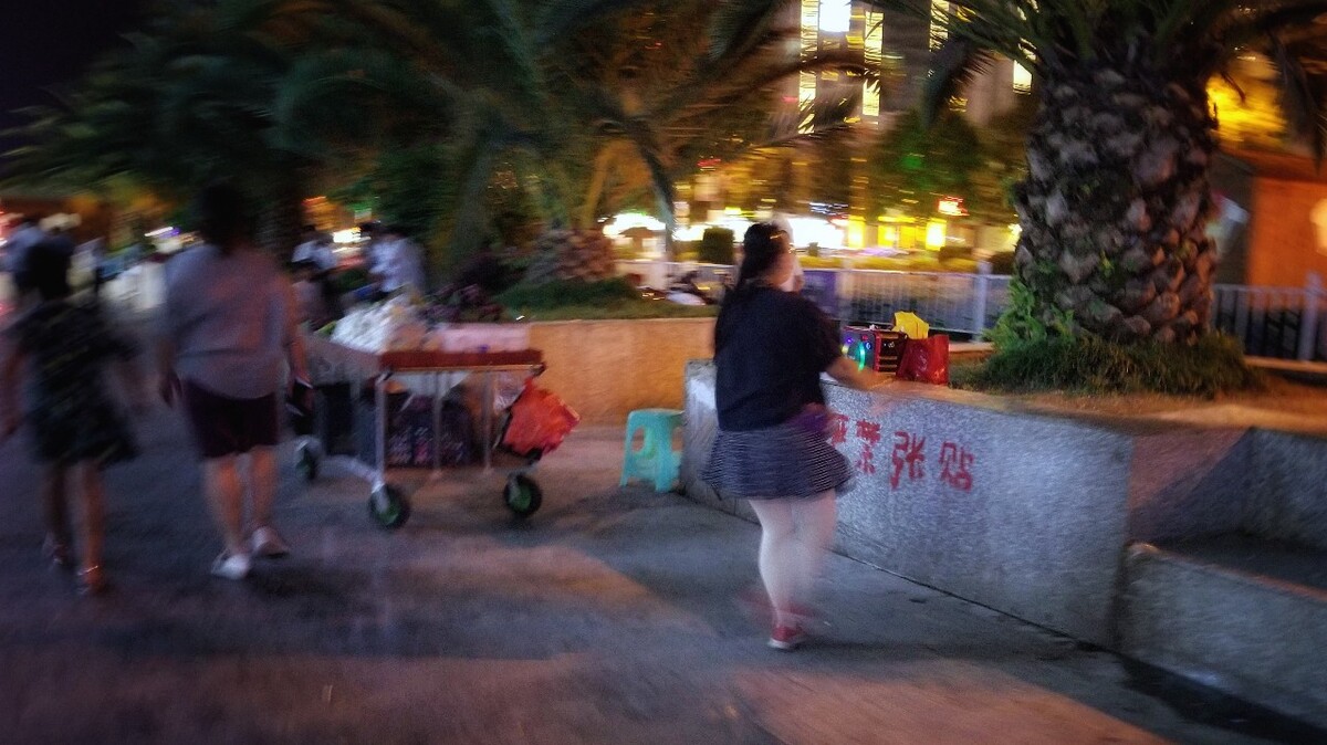深夜的街头，一个卖水果的商贩趁没生意，开着音响跳起了舞蹈。