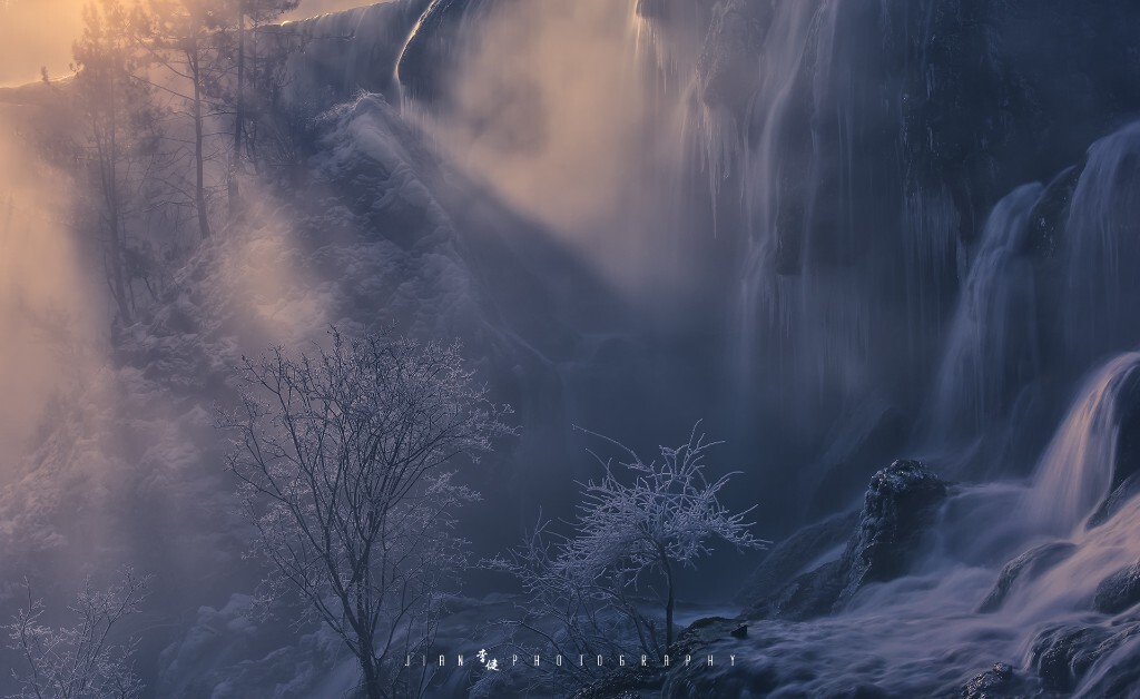 清早温暖的阳光透过树枝洒在结冰的瀑布上，升腾的水汽凝结在小树上行程美丽的雾凇，整个场景就像梦幻的仙境。