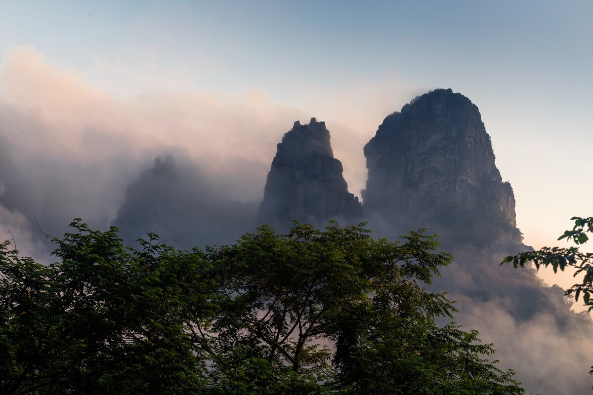 清晨的山顶，云雾弥漫不见山影，太阳出来了，云雾一点点散去，露出山的身影。