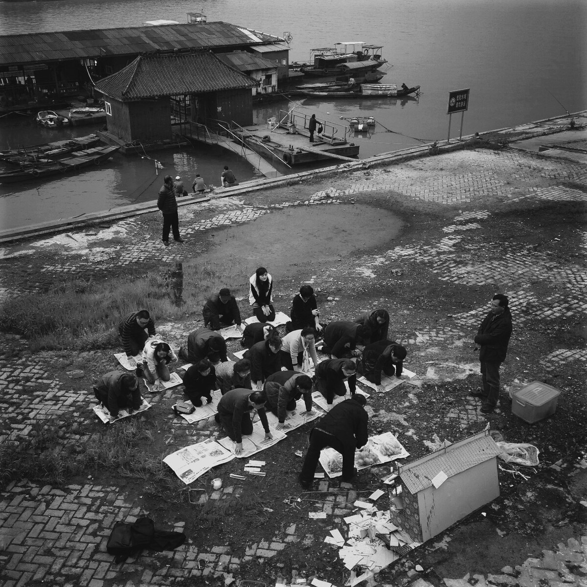        2015年3月23日，长沙市万达广场湘江边，一大家族人跪在报纸上举行祭祖仪式。