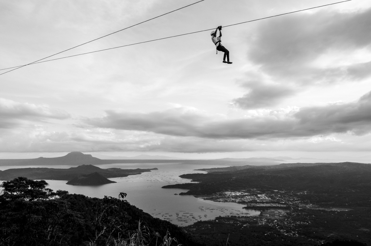 这是一位玩高空溜索的游客,远处就是塔阿尔湖.