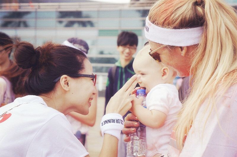 陌生人之爱。广州，color run 的活动中，聚集了来自世界各地的人，大家都沉浸在欢乐的五彩海洋中。图片为一个年轻的姐姐在逗一个老外的可爱baby