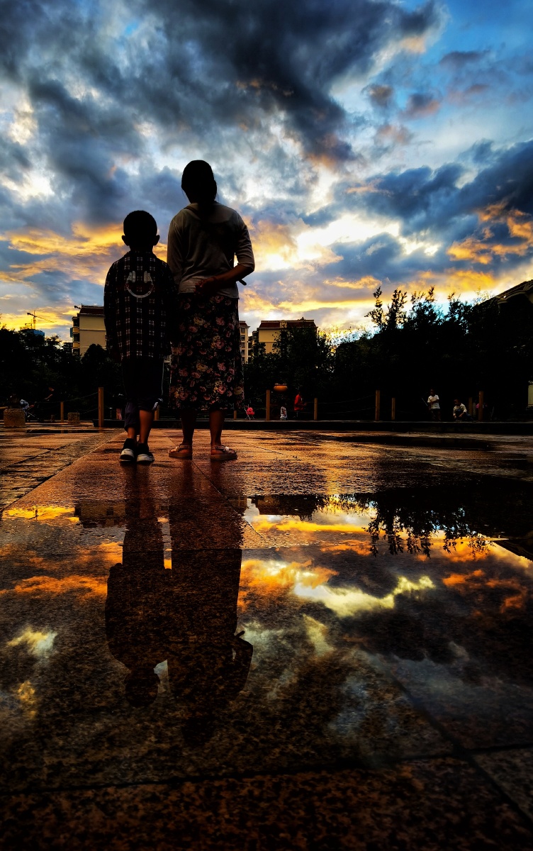 黄昏雨后散步至小区广场,利用晚霞和水影构图,加入人文元素,试图营造