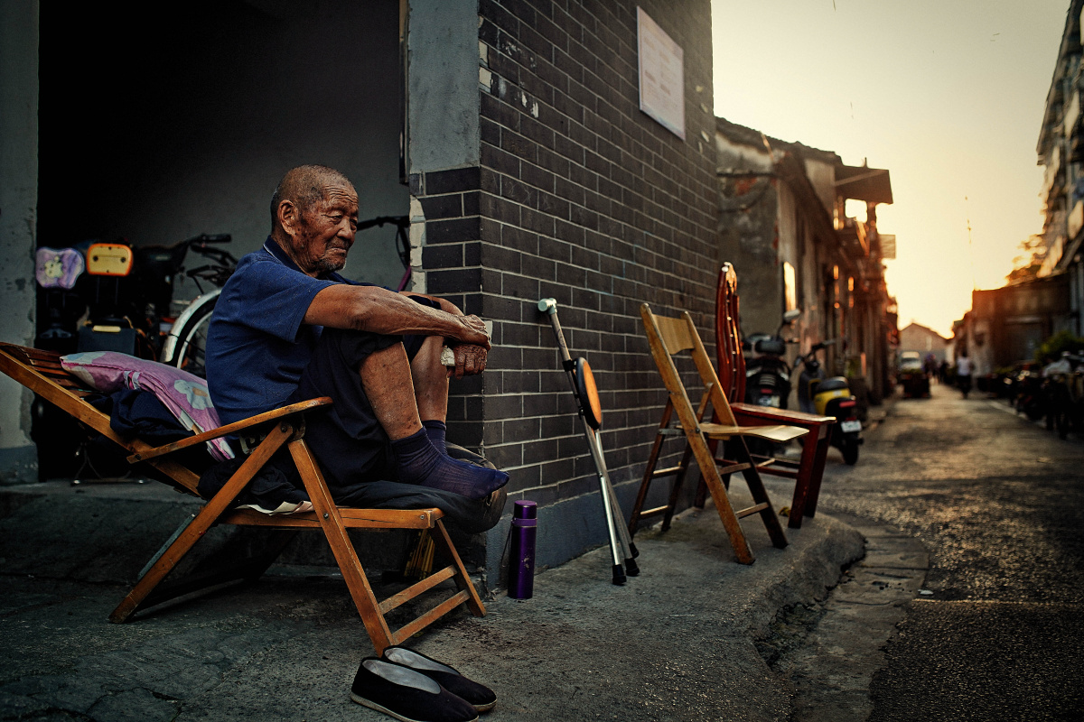 黄昏时分老城区的小巷里,一位坐在躺椅上的老人肖像.