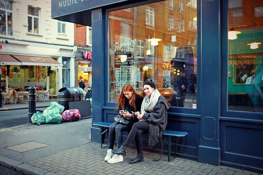 Two girls sitting outside shop