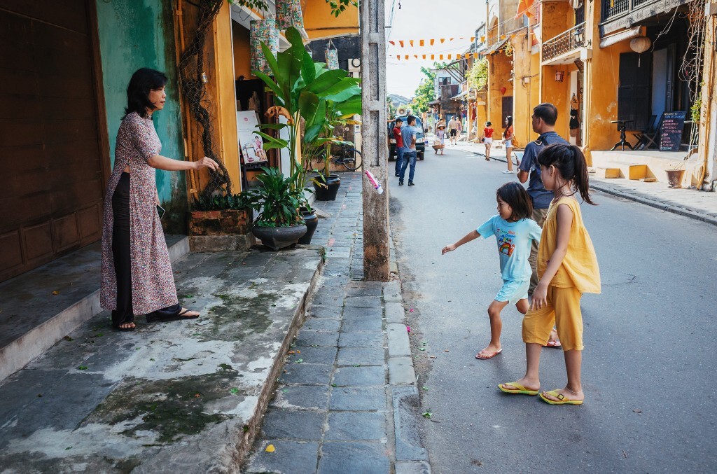 会安的街头巷尾。一个母亲陪自己的两个女儿在踢毽子。<br />
2015.12.1 RICOH GR