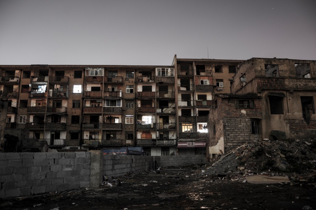 The building was ready to be pulled down. However, you could find some lights were still on. The people who still lived in this building had the interest conflict with the government. They would like to earn more but the government said no.