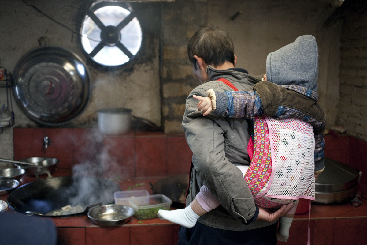 农家的大叔背着娃娃在炒菜