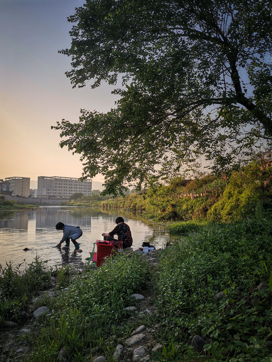 清晨,小河边迎着晨曦洗衣的大妈