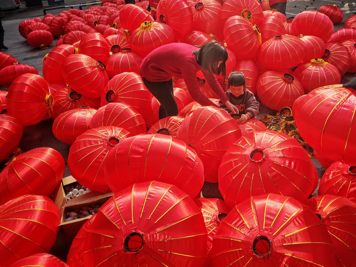 2021年四川绵阳街头正准备新年挂灯笼的一家人.