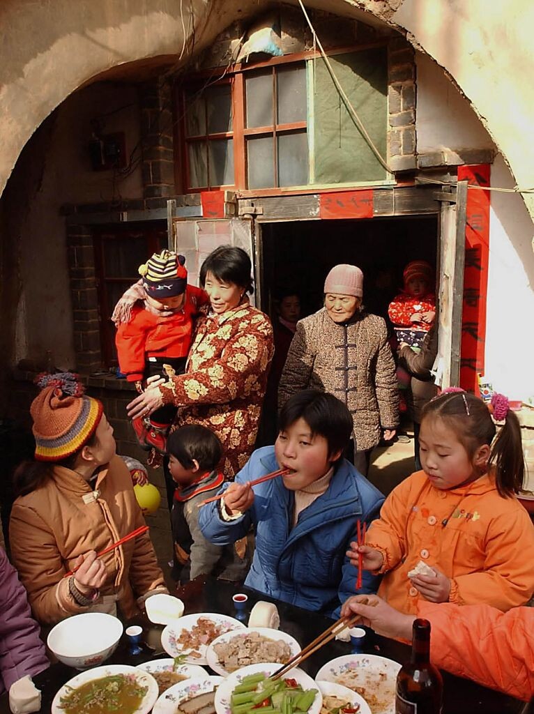 年夜饭<br />
2003年2月1日,在河南省陕县张汴乡曲村,一户村民在土窑洞外的院子里吃年饭。与其他地区习惯在除夕晚上吃“年夜饭”的风俗有所不同,中原地区的百姓大多是在初一中午吃年饭。这也是一年中全家大团圆的宴会。