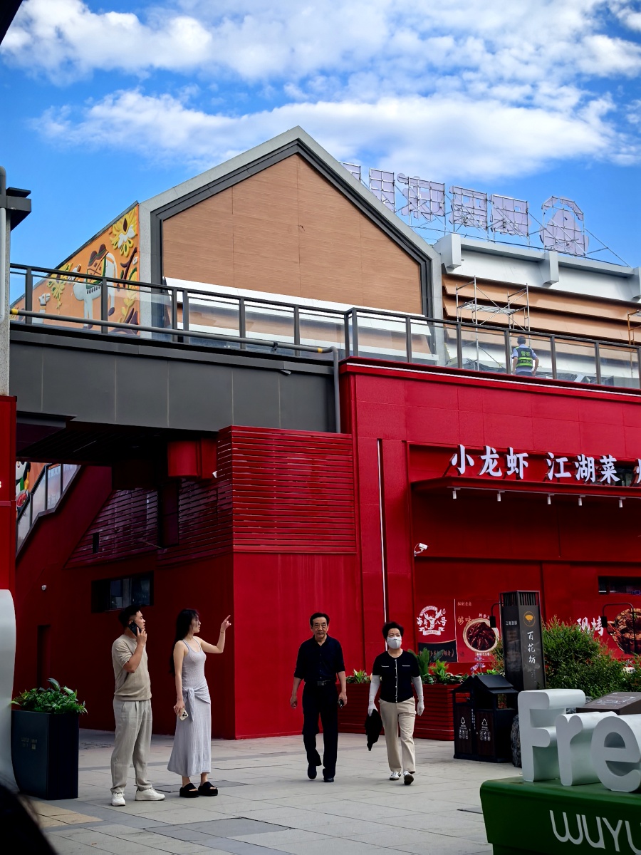 画面定格于城市商圈一角，鲜红的小龙虾江湖菜门店在晴空下格外醒