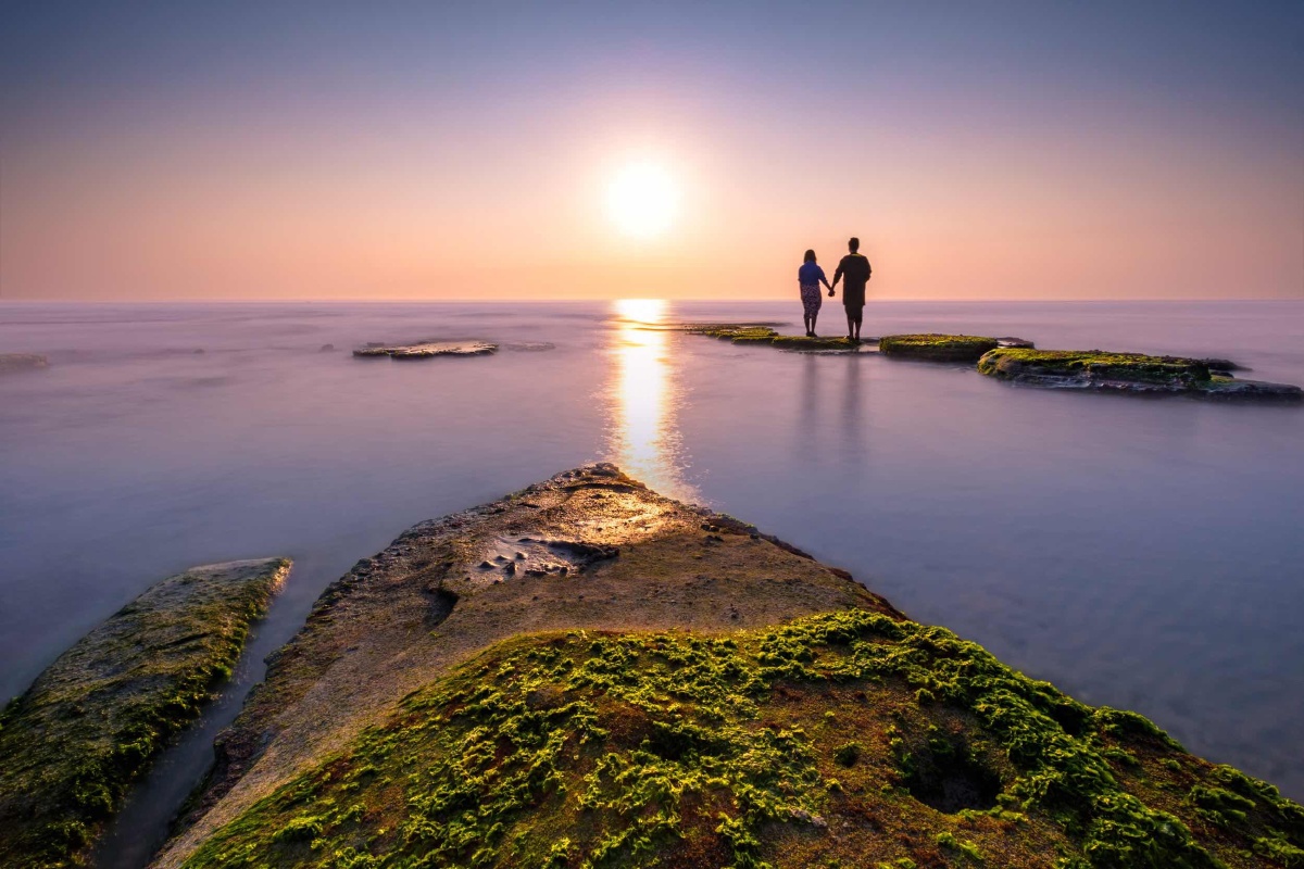情人节的涠洲岛,一对情侣牵着手一起看着夕阳,画面是那么