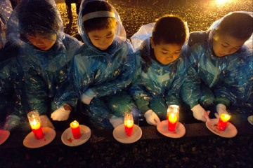 孩子们放置点燃的蜡烛，愿逝者安息