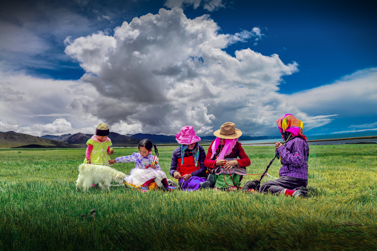 妇女手里拈着毛线儿童玩耍小羊羔吃着嫩草好一个悠闲惬意的生活情景