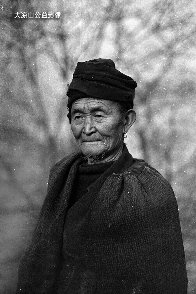 戴着小耳环,裹着优雅的小头巾,穿着"擦尔瓦"(彝语意为批毡),摄于寒冬.