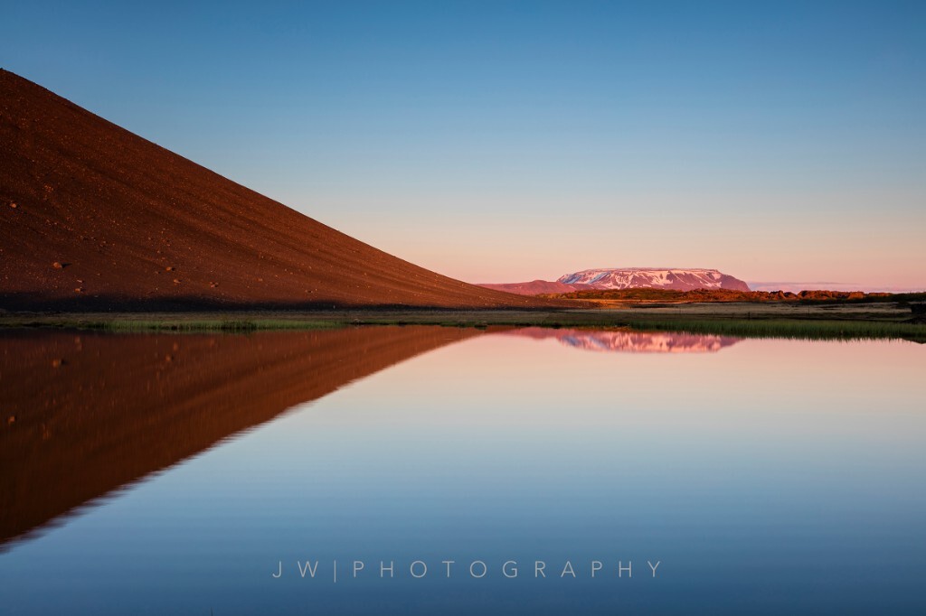 冰岛北部米湖附近，Hverfjall火山与远景的平顶雪山在平静的湖水反射下组成了完美的几何图形。