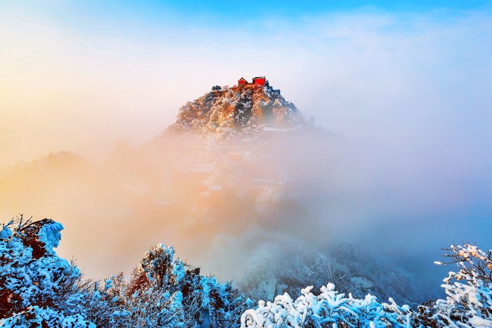 雪后初晴，云蒸雾绕，武当山金顶在夕阳照耀下在云雾中偶露尊容，真如天庭仙境